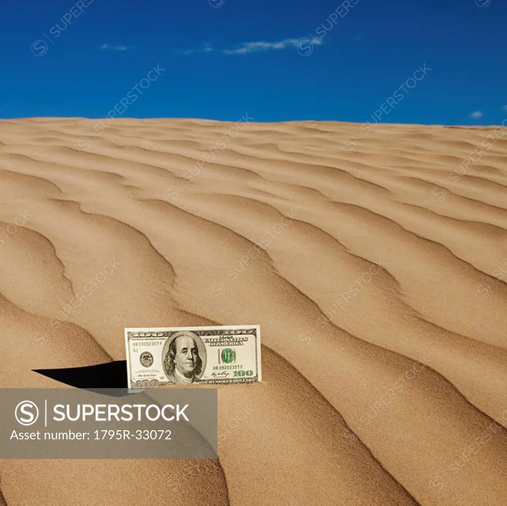 100 dollar bill on sand in desert
