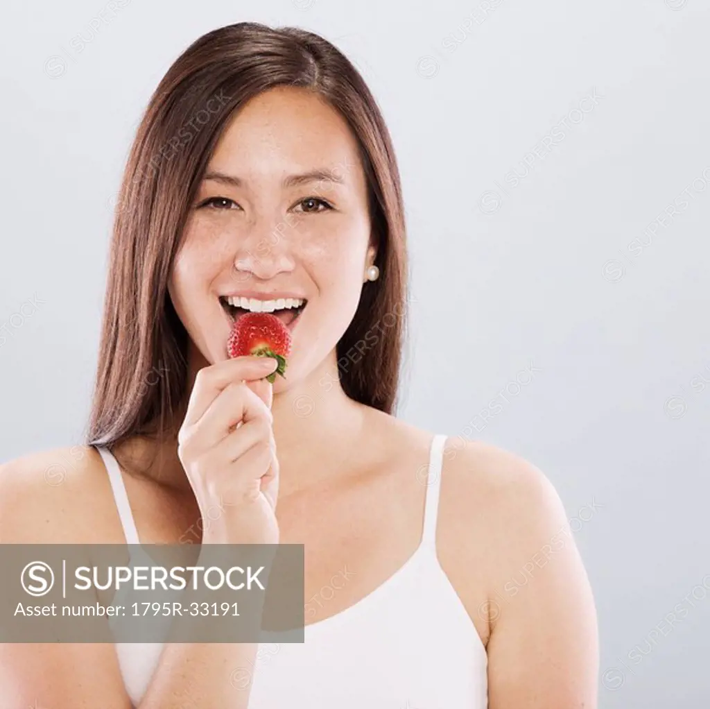 Brunette woman eating a strawberry