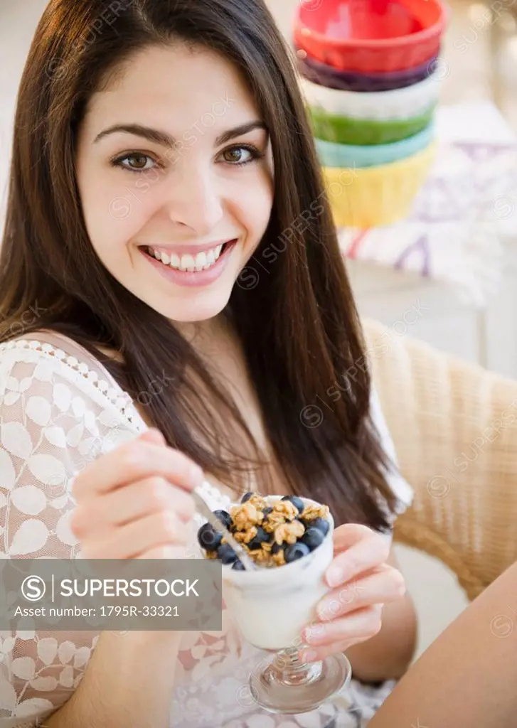 Brunette woman eating granola and yogurt