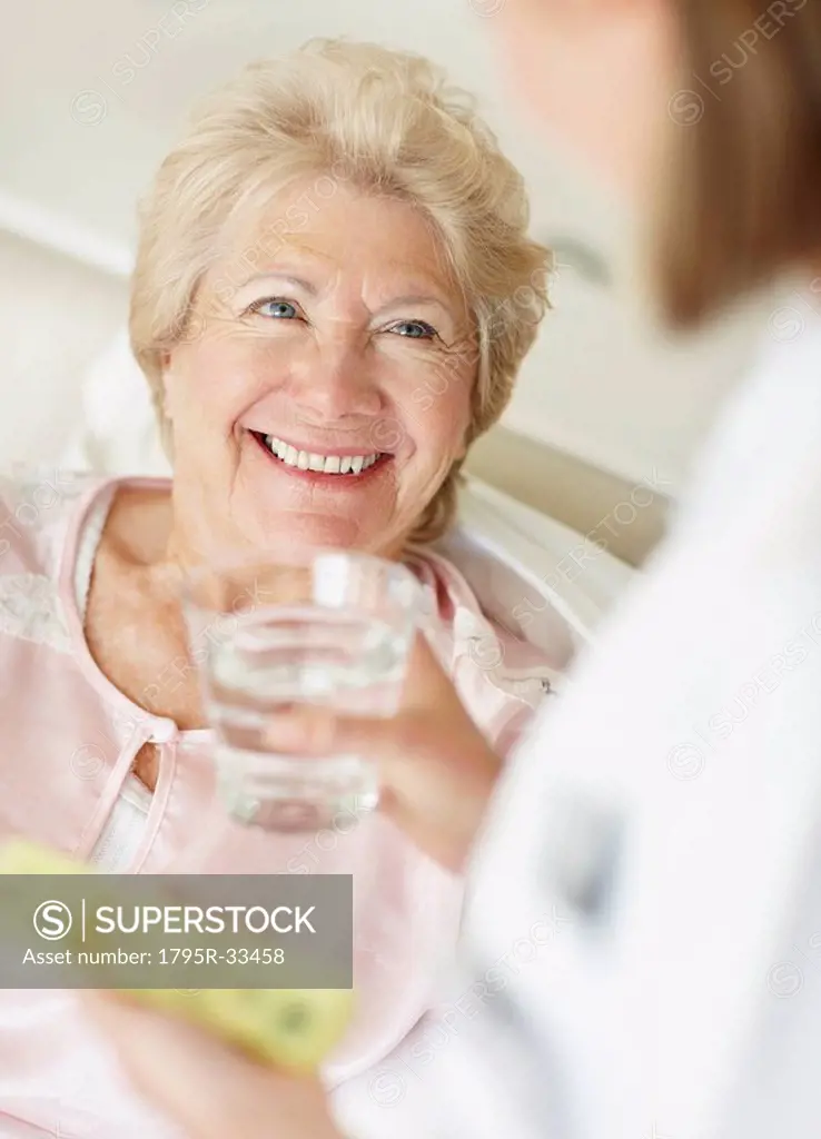 Nurse giving pill to senior woman