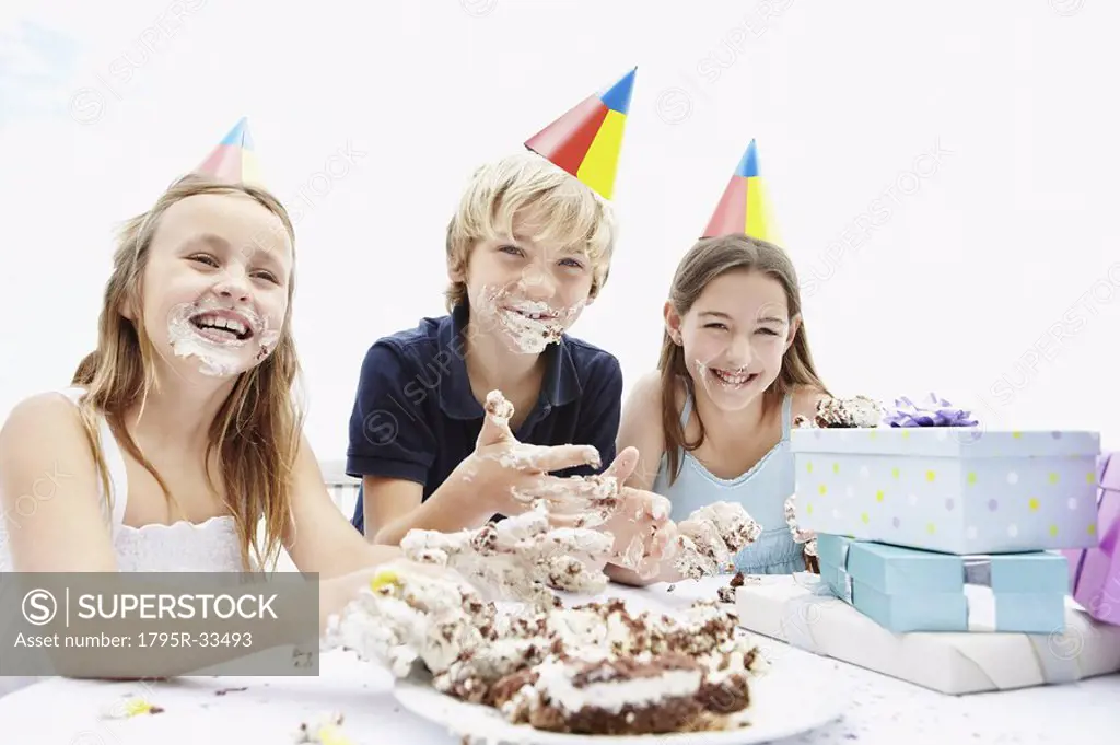 Children eating birthday cake with their hands
