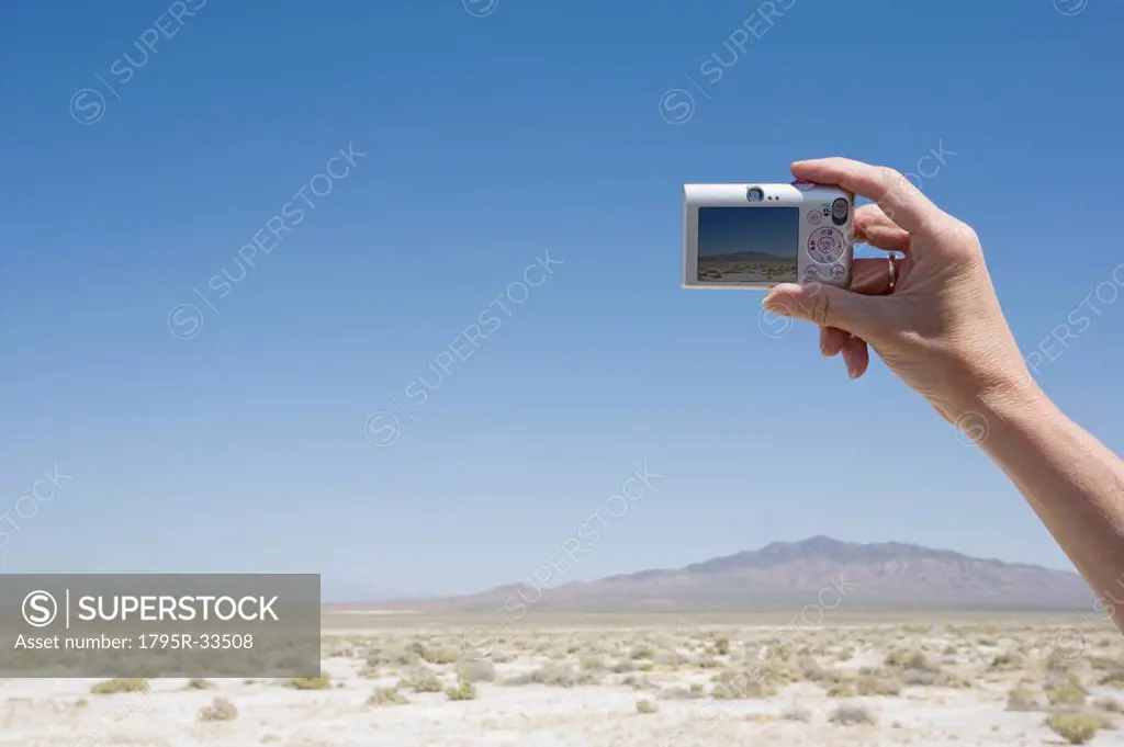 Hand holding a camera in the desert