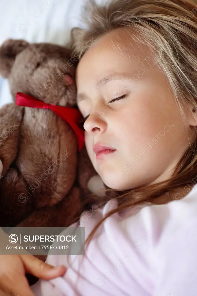 Sad girl 10_11 sleeping in bed with teddybear