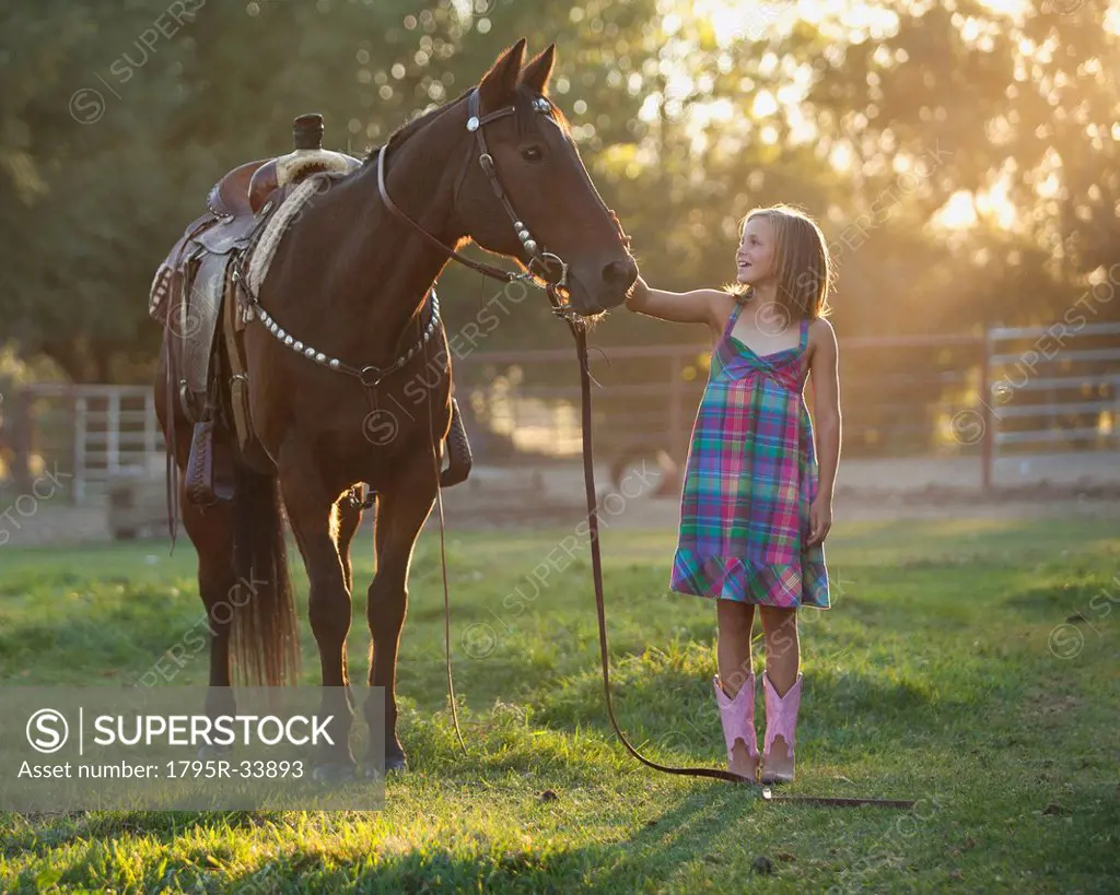 Girl 8_9 stroking horse in paddock