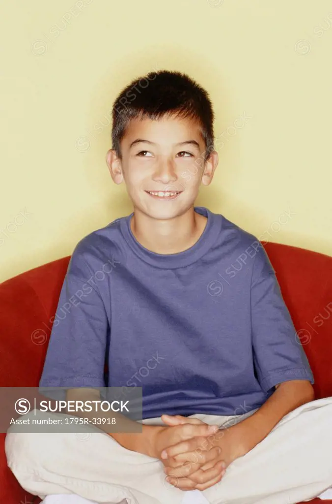 Cute young boy sitting in red chair
