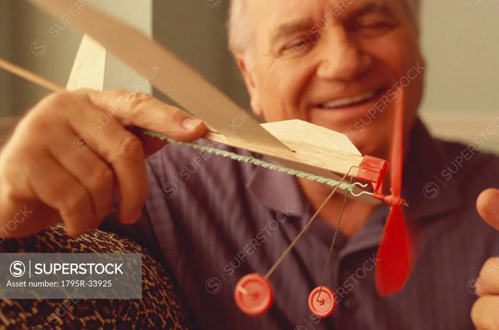 Senior man playing with toy airplane