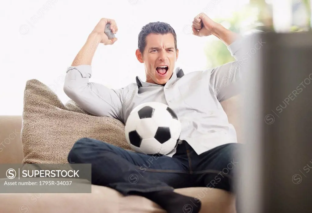 Mid adult man watching football match on television