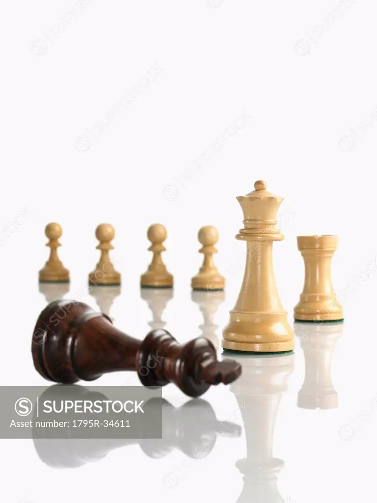 Defeated king chess piece with opposing queen, rook and pawns