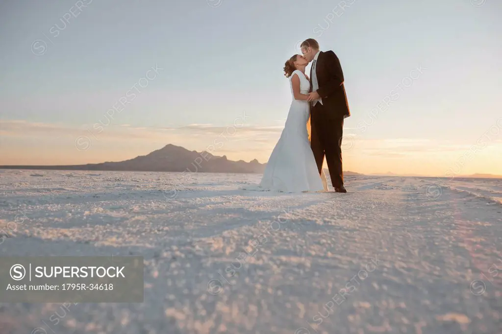 Groom kissing bride in desert