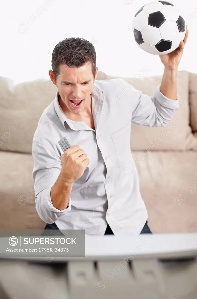 Mid adult man watching football match on television
