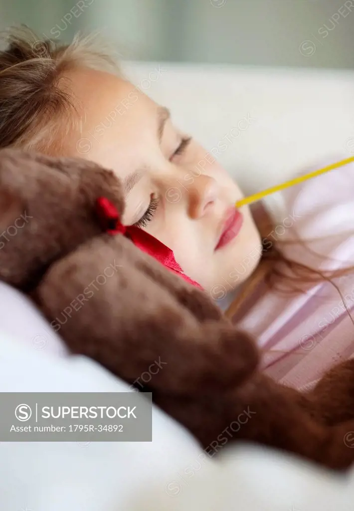 Sad girl 10_11 lying in bed with teddybear and thermometer in mouth