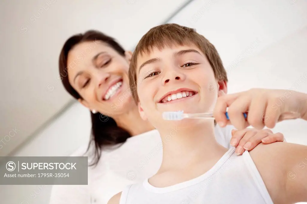 Mother embracing son 12_13 while he is brushing teeth