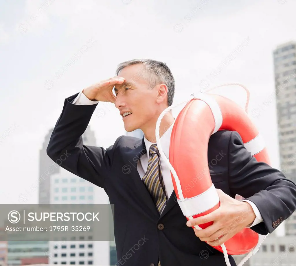 Businessman looking away and holding life belt