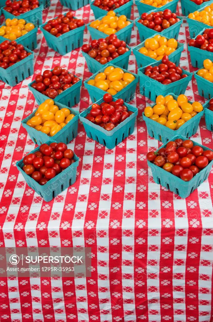 Boxes with cherry tomatoes on table