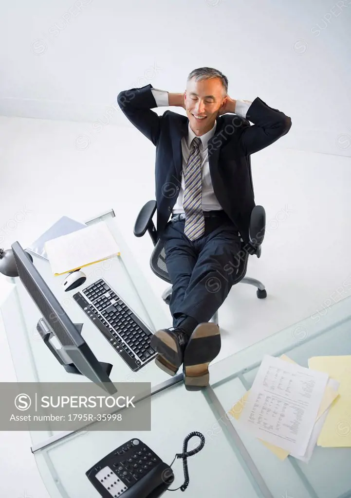 Businessman with feet on desk smiling