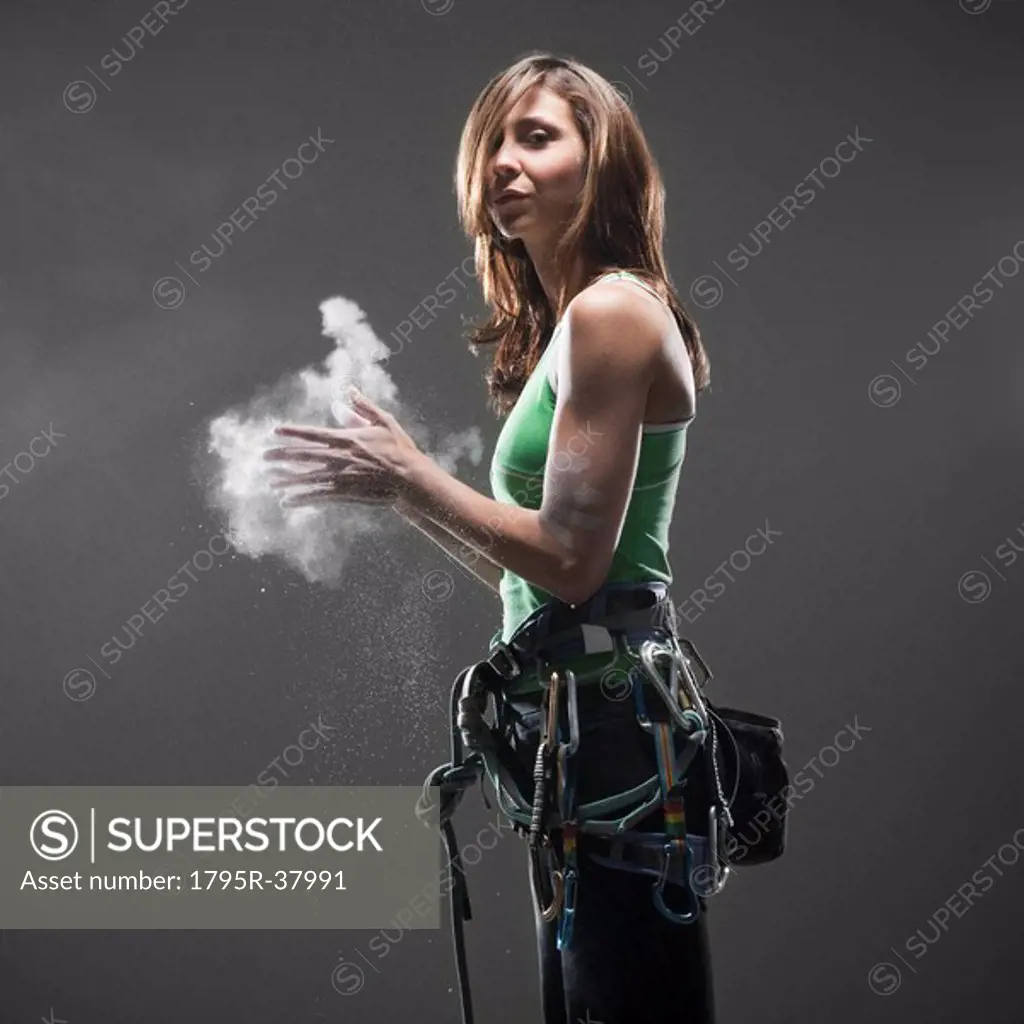Woman with climbing gear putting chalk on hands