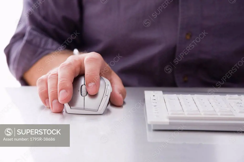 A hand on a computer mouse by a keyboard