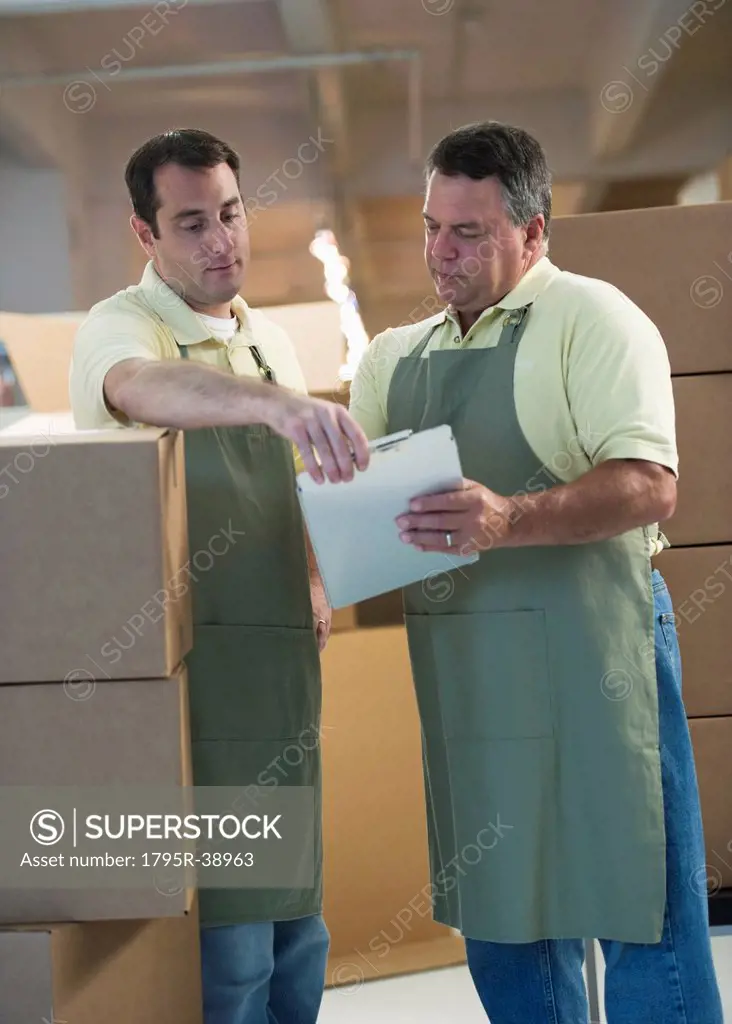 USA, New Jersey, Jersey City, Two male warehouse workers by stacked boxes