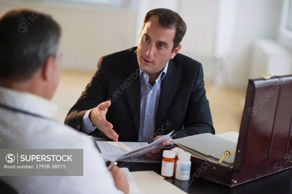 USA, New Jersey, Jersey City, Medical sales representative talking with doctor in office