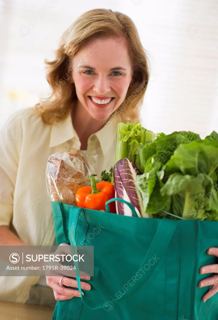USA, New Jersey, Jersey City, Portrait of woman holding grocery bag in kitchen