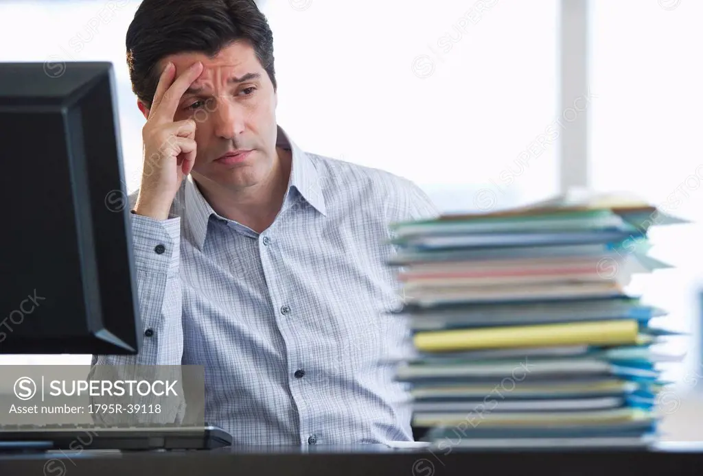 USA, New Jersey, Jersey City, Businessman staring at stacked paperwork on desk