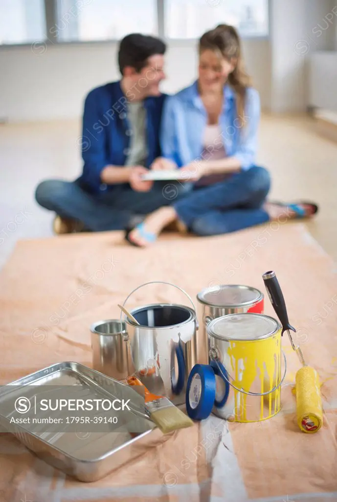 USA, New Jersey, Jersey City, Couple sitting near painting equipment in new home