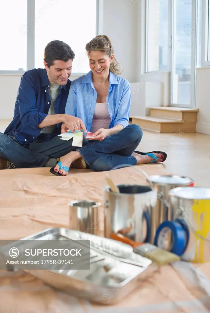 USA, New Jersey, Jersey City, Couple sitting near painting equipment in new home