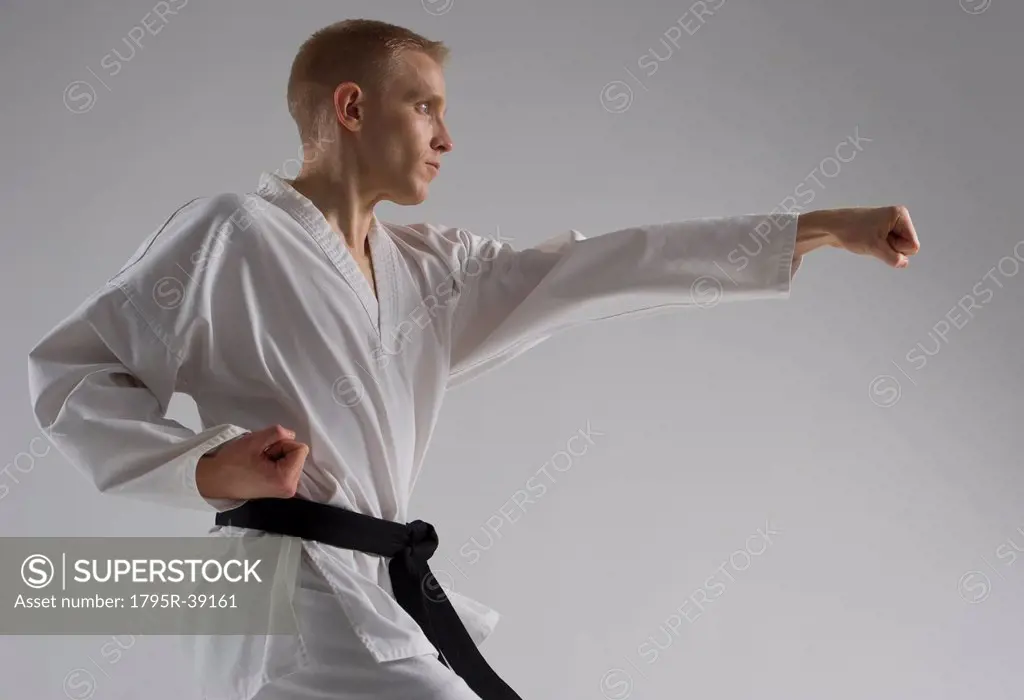 Young man performing karate stance on white background