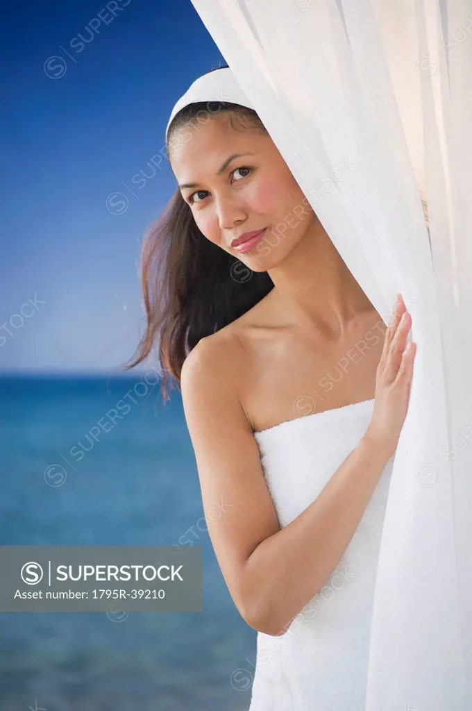 USA, New Jersey, Jersey City, Portrait of woman peering around curtain near sea
