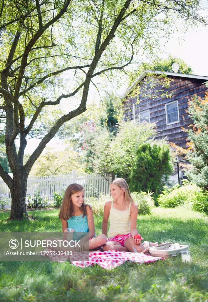 USA, New York, Two girls 10_11, 10_11 sitting on blanket in backyard