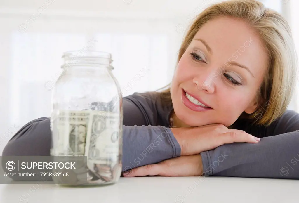 USA, New Jersey, Jersey City, Young attractive woman watching improvised jar _ piggybank