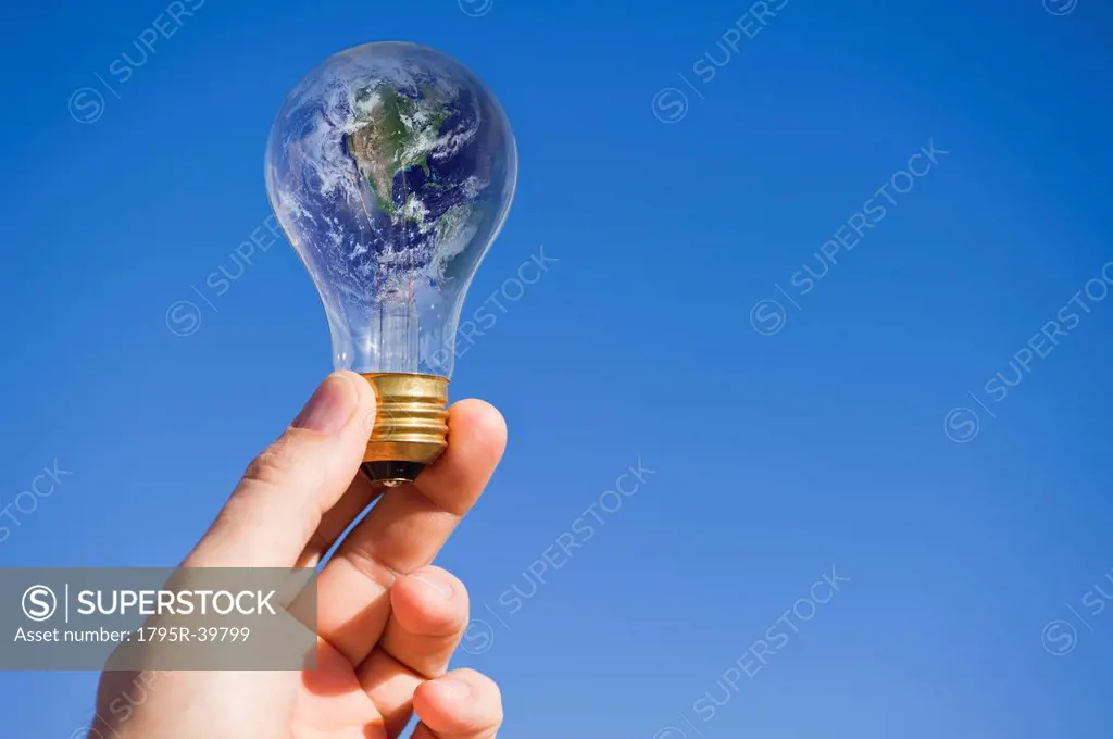Hand holding lightbulb with globe