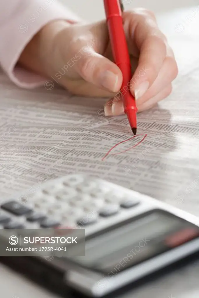 Woman checking financial page with calculator