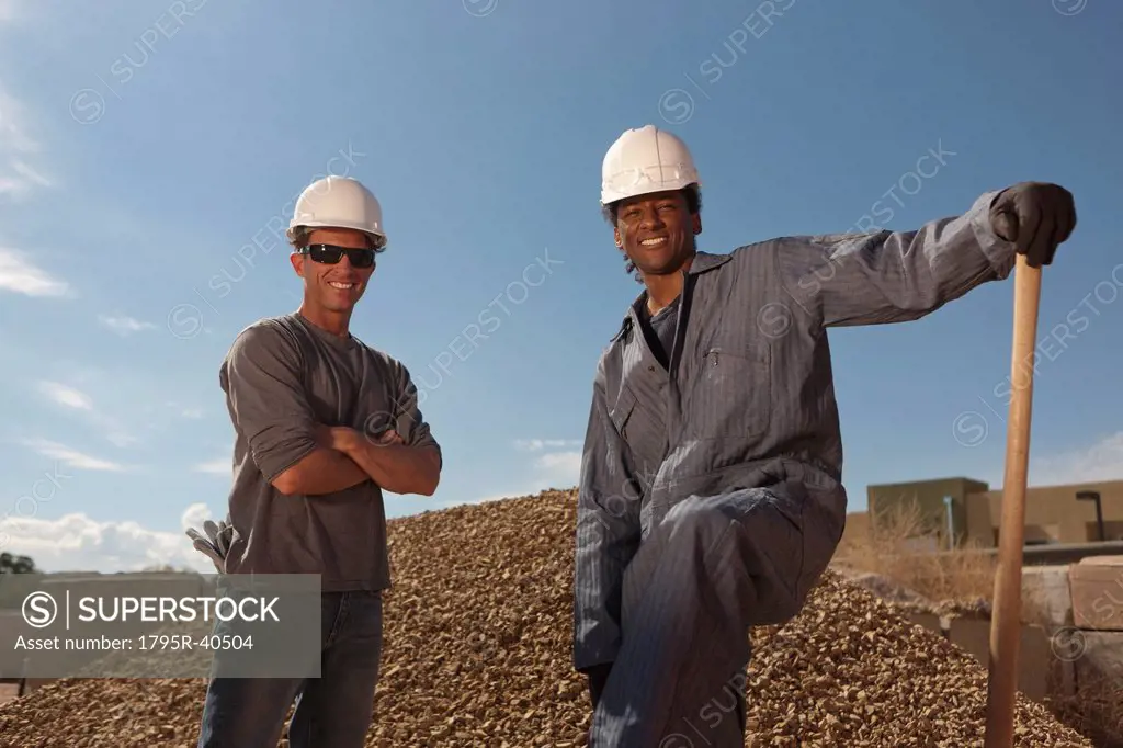 Portrait of two construction workers by rubble on building site