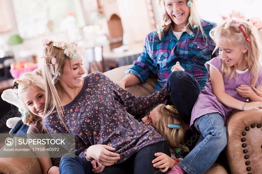USA, Utah, family portrait of sisters 6_7, 8_9, 12_13, 14_15, 16_17 on sofa having fun