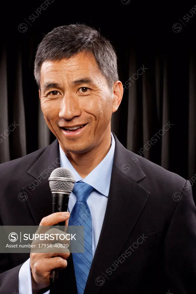 USA, Utah, Provo, Portrait of businessman with microphone standing in front of black curtain
