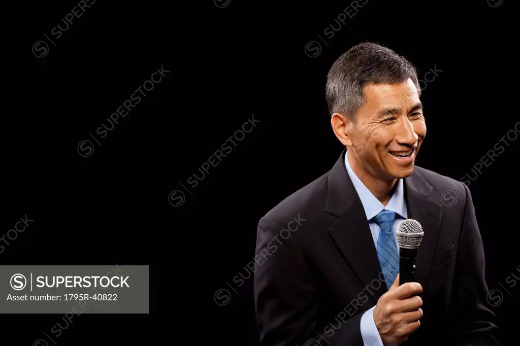 USA, Utah, Provo, Smiling businessman with microphone standing ion stage