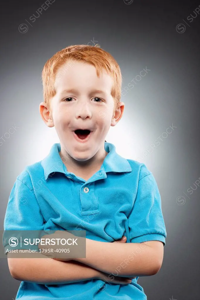 Portrait of smiling redhead boy 4_5 wearing blue polo shirt and making face, studio shot
