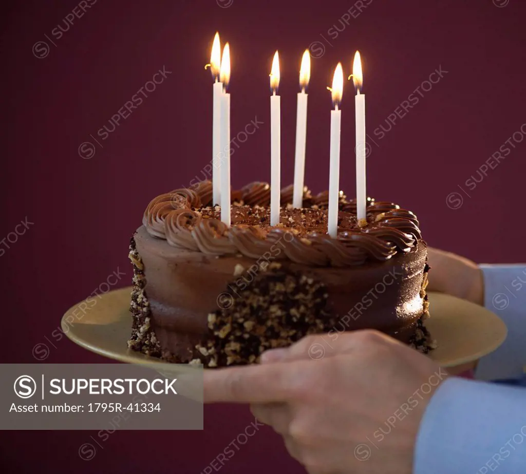 Studio shot of man holding chocolate birthday cake