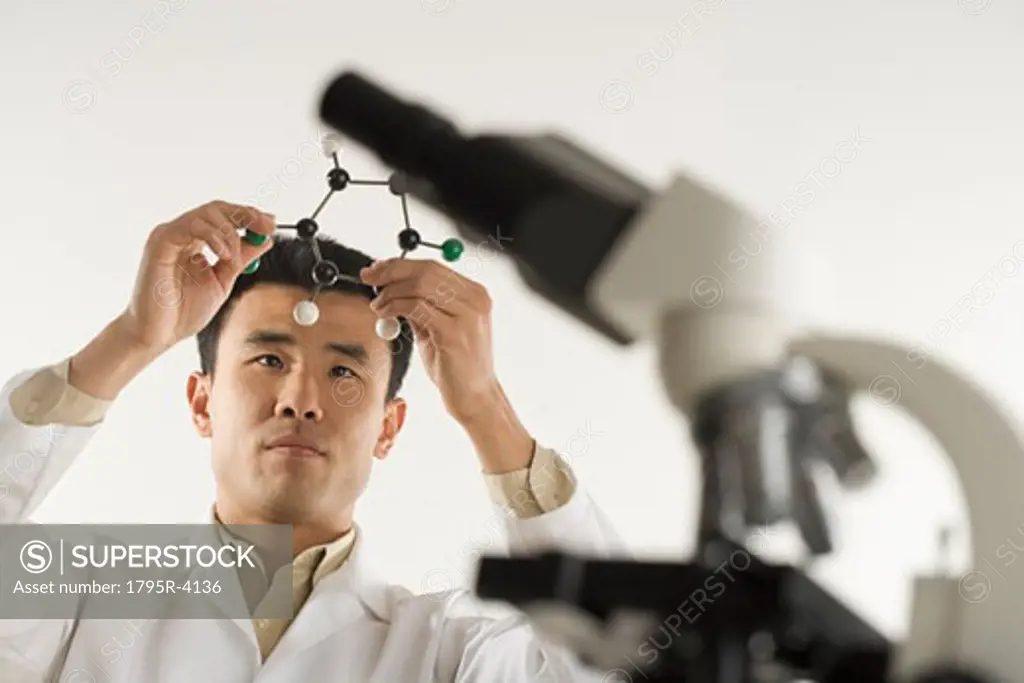 Scientist with microscope holding molecular model