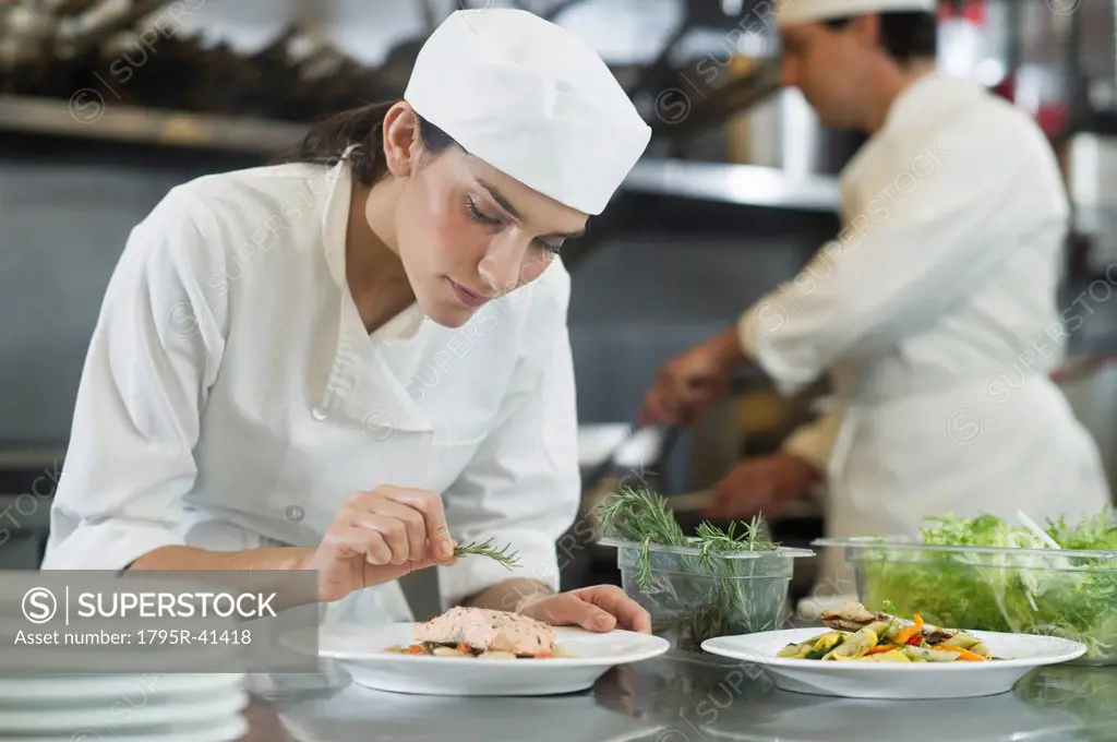 Chef and cook preparing food in commercial kitchen