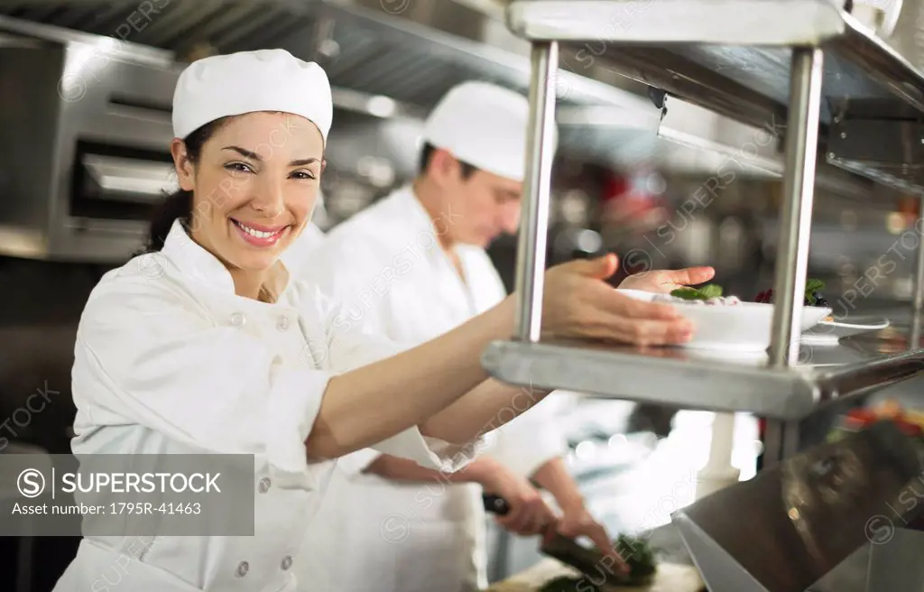 Chefs preparing food, woman looking at camera and smiling