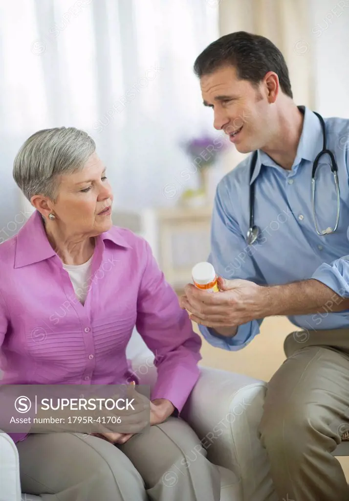 Smiling doctor giving medicine bottle to senior woman