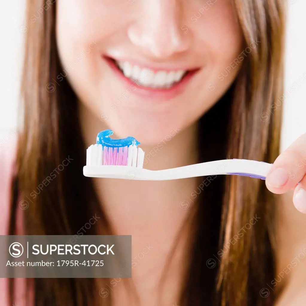 Close_up of smiling young woman holding toothbrush