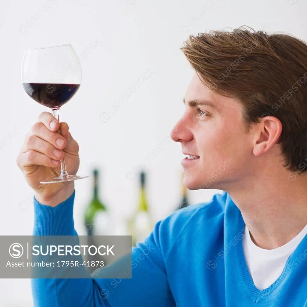 Young man examining red wine