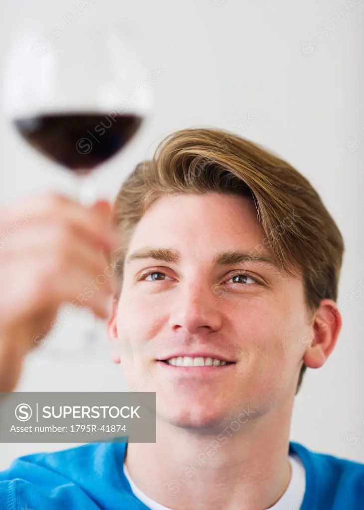 Young man examining red wine