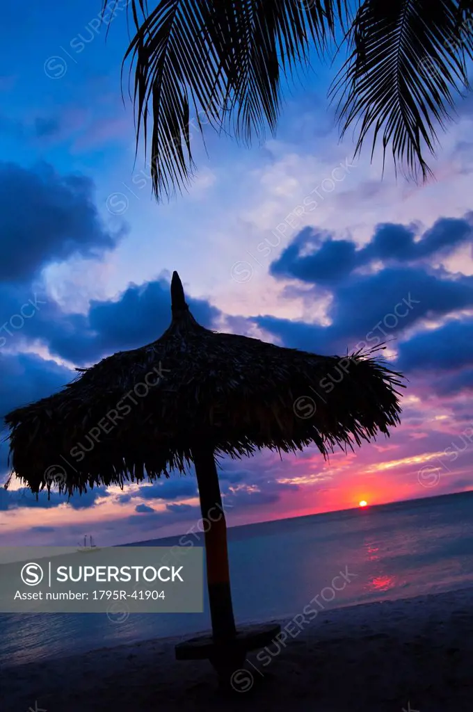 Aruba, silhouette of palapa on beach at sunset