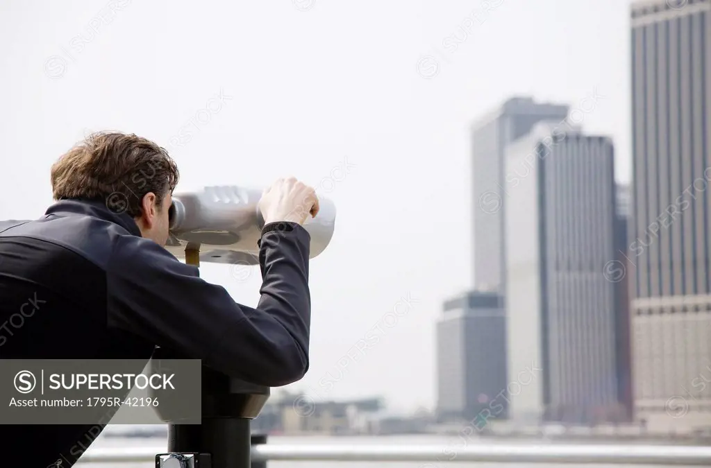 USA, New York City, Manhattan, man looking at skyline through telescope