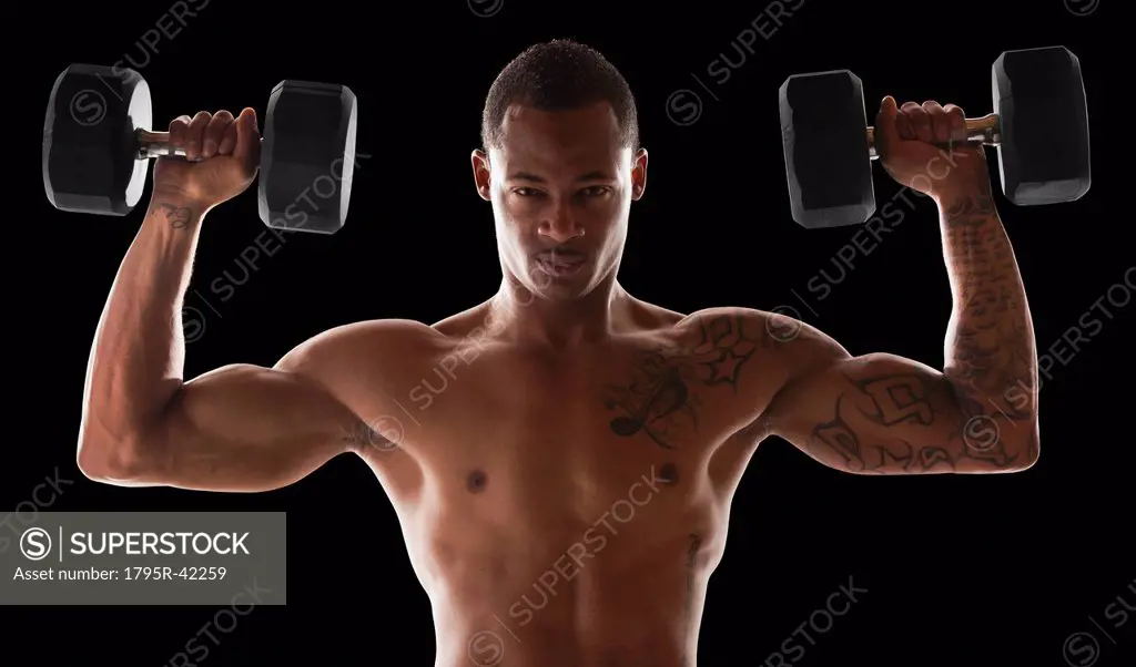 Studio shot of muscular man exercising with dumbbells