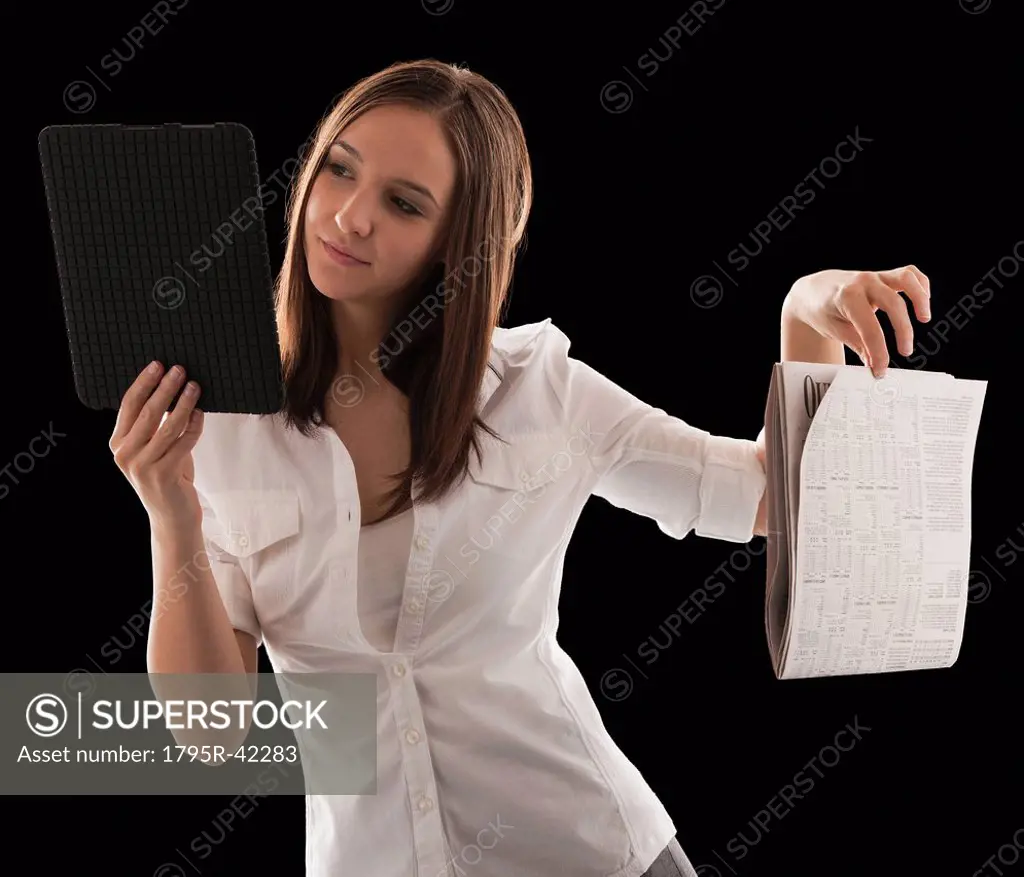 Young attractive businesswoman comparing financial results with financial column in newspaper